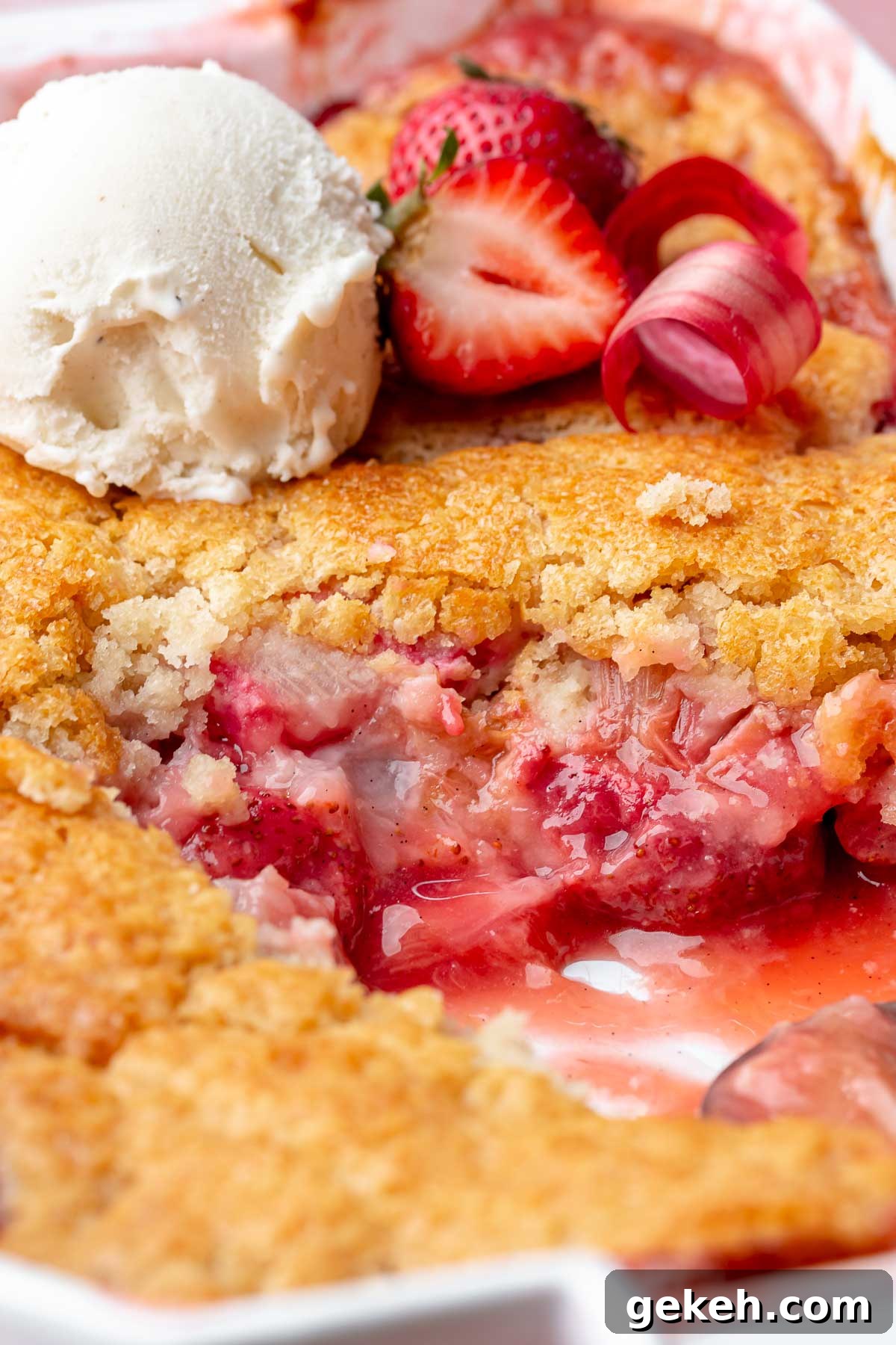 Strawberry Rhubarb Cobbler Recipe: Classic Summer Dessert 2 Strawberry rhubarb cobbler in a casserole dish with a scoop removed and ice cream on top.