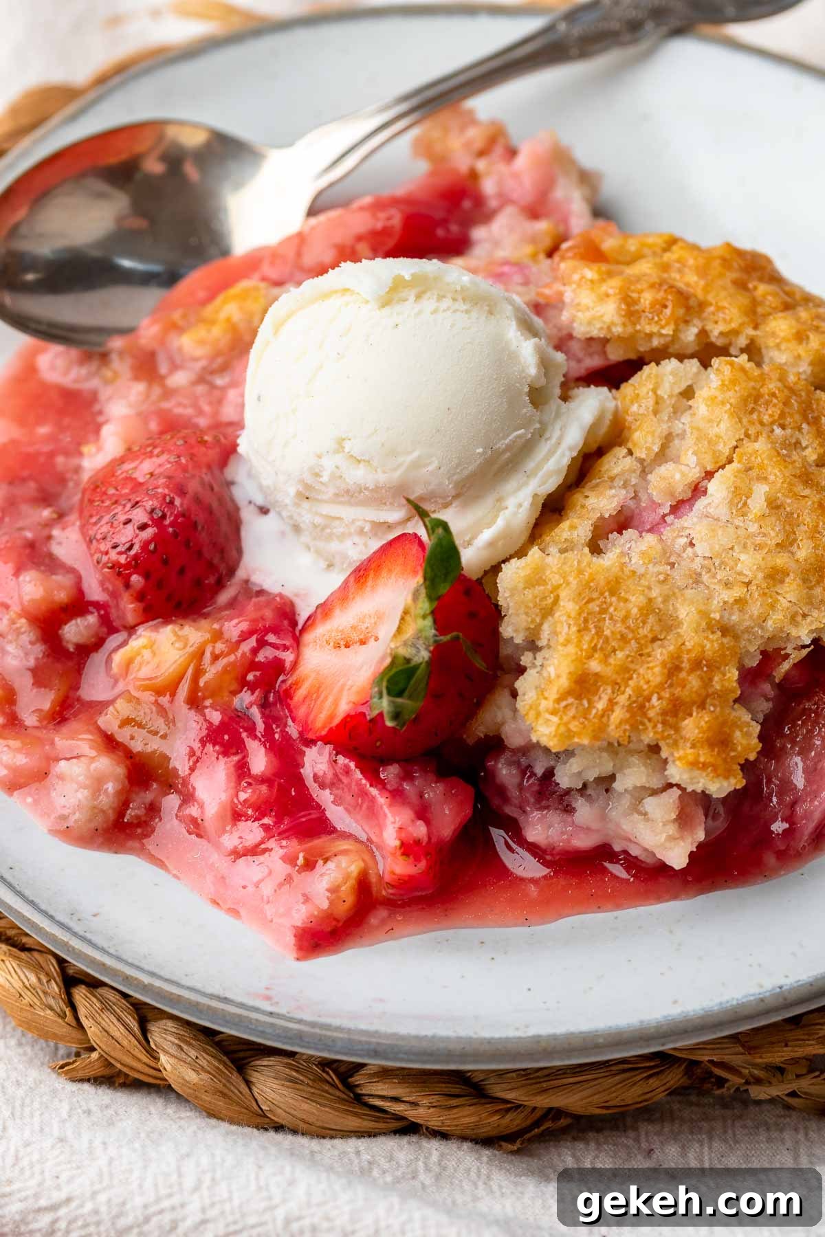 Strawberry Rhubarb Cobbler Recipe: Classic Summer Dessert 11 Strawberry rhubarb cobbler on a plate with a scoop of vanilla ice cream on top.