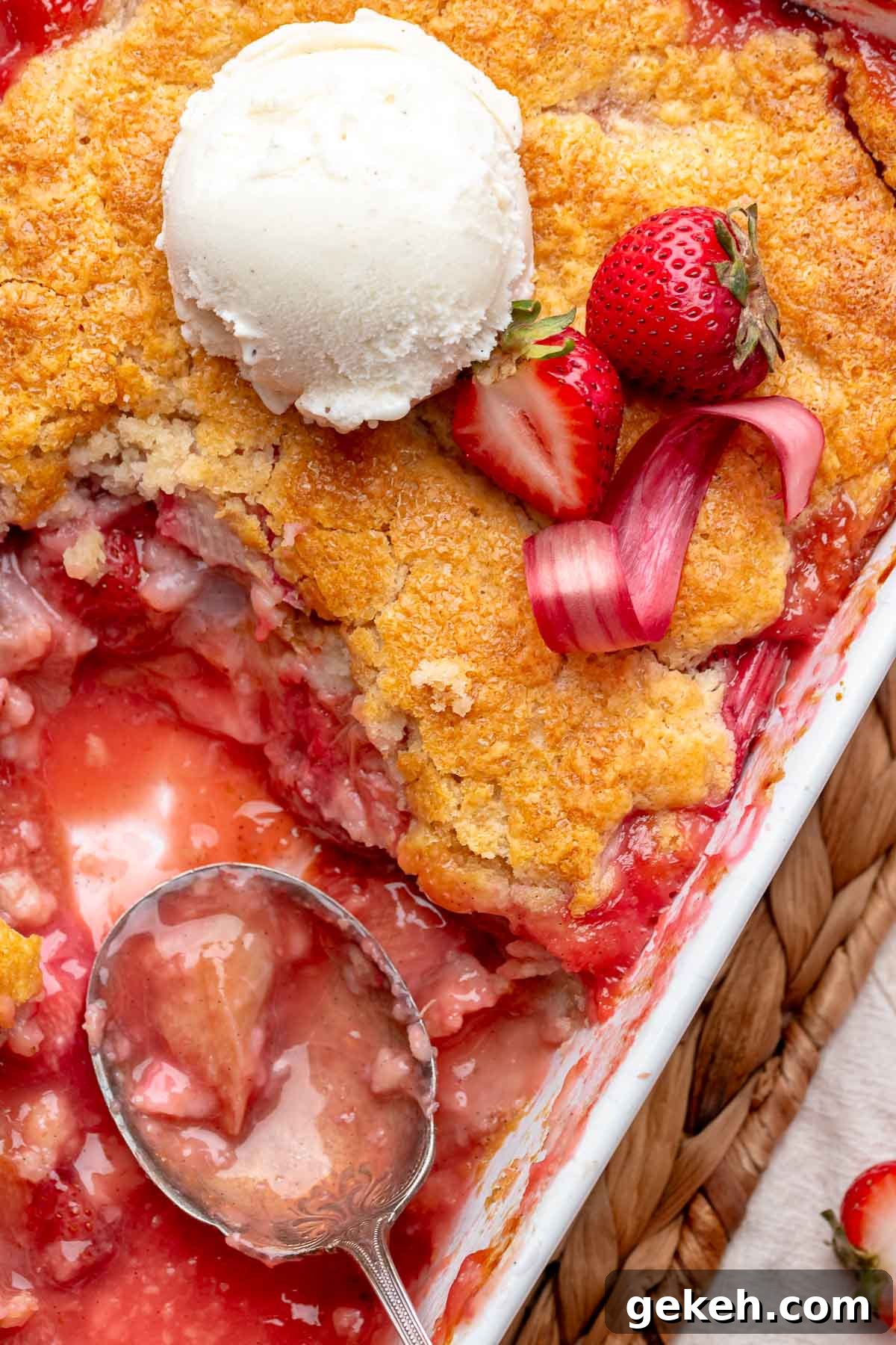 Strawberry Rhubarb Cobbler Recipe: Classic Summer Dessert 9 A spoon sits in a casserole dish of strawberry rhubarb cobbler with some removed.
