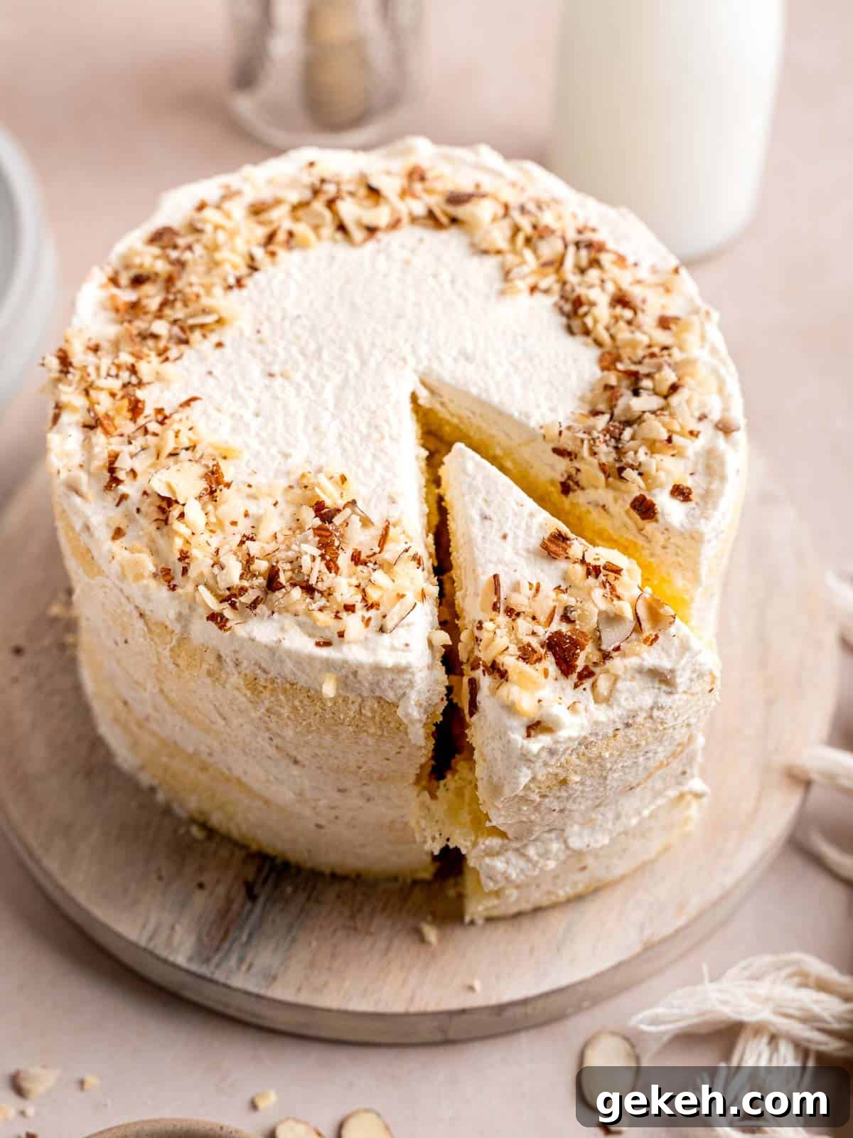 Homemade Almond Cream Cake Recipe for Moist, Decadent Slices 12 An almond cream cake on a cake stand with a slice cut out.