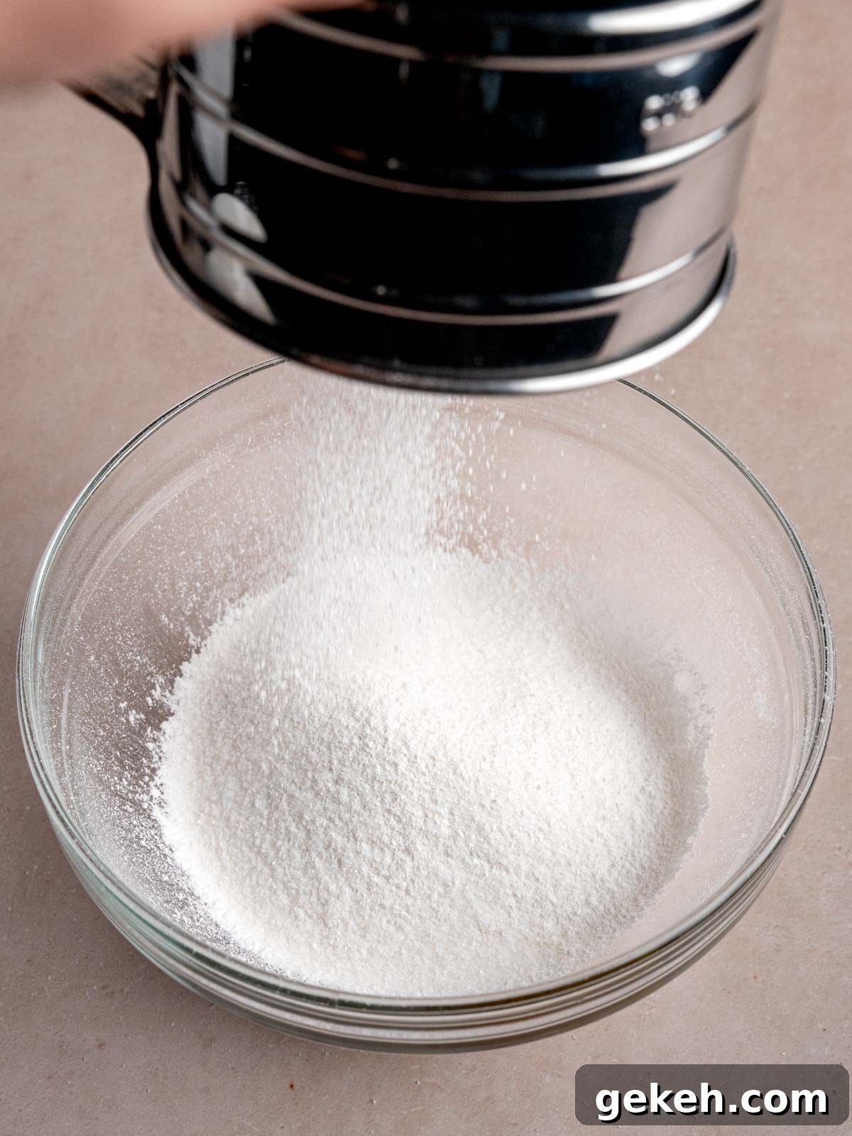 Homemade Almond Cream Cake Recipe for Moist, Decadent Slices 6 Sifting a cake flour mixture into a bowl.