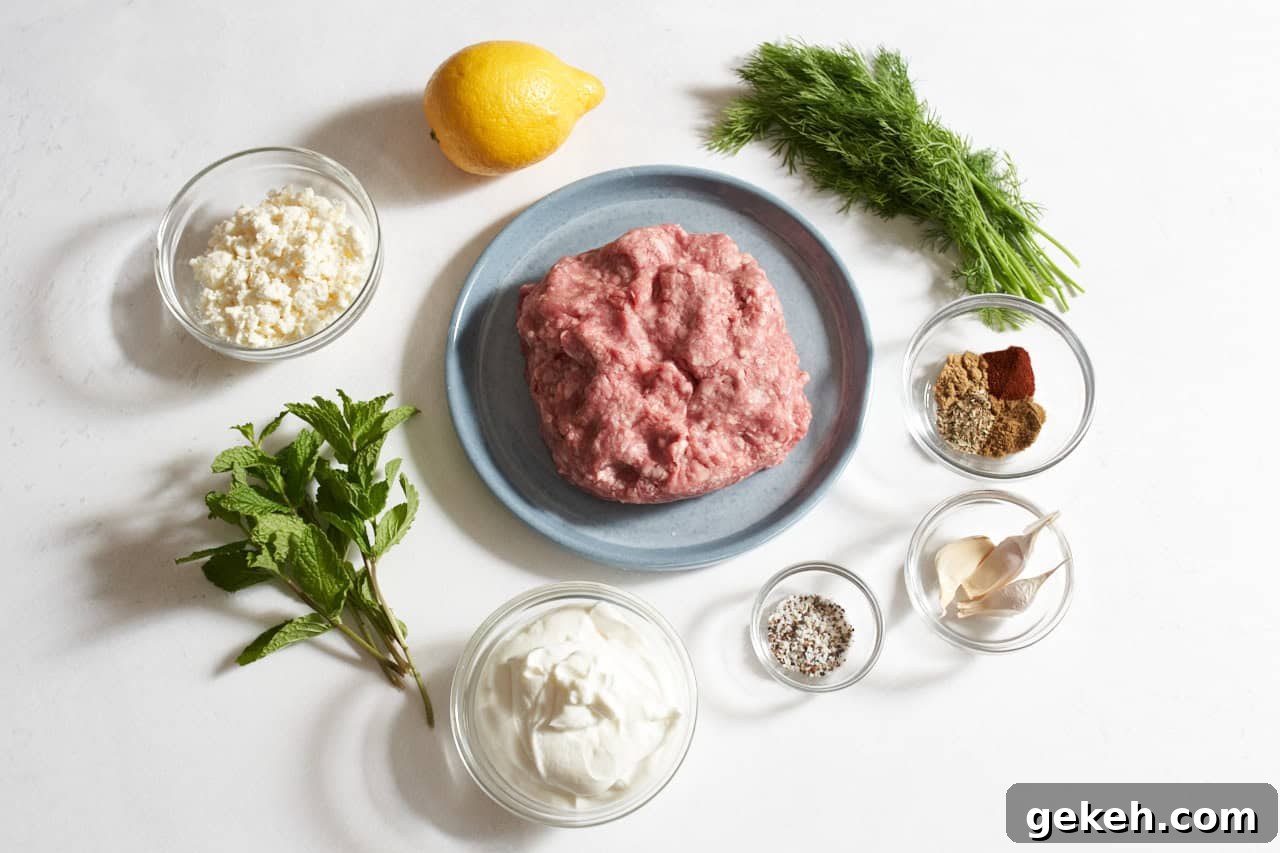 Juicy Ground Lamb Burgers with Creamy Feta Sauce 3 A plate of ground lamb surrounded by fresh dill and mint, a lemon, and small bowls of spices, garlic, yogurt and feta.