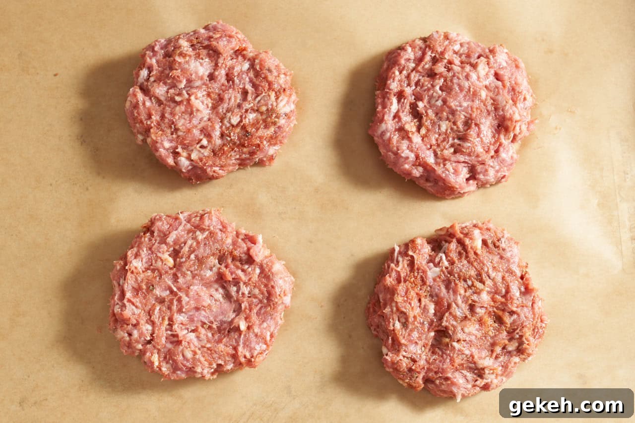 Juicy Ground Lamb Burgers with Creamy Feta Sauce 5 Four uncooked lamb burger patties on brown parchment paper.