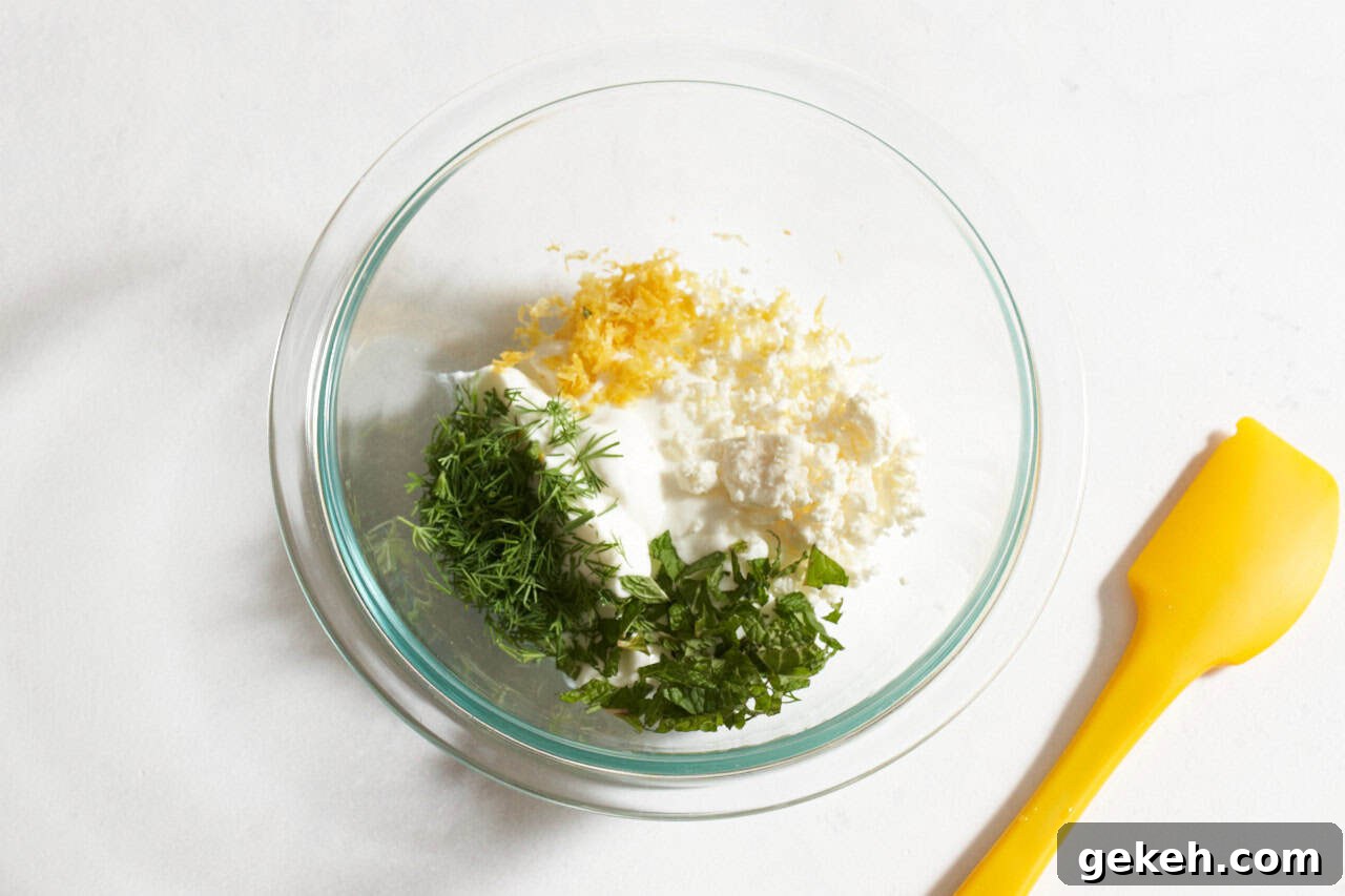 Juicy Ground Lamb Burgers with Creamy Feta Sauce 6 A bowl of ingredients including Greek yogurt, feta, lemon zest and fresh herbs.