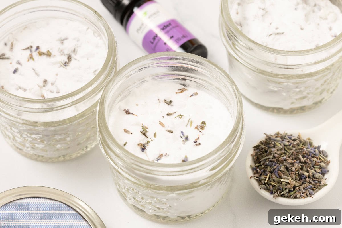 DIY Baking Soda Air Freshener with Natural Scents 7 mason jars of homemade air freshener with a bottle of lavender essential oil and a spoonful of lavender buds next to it