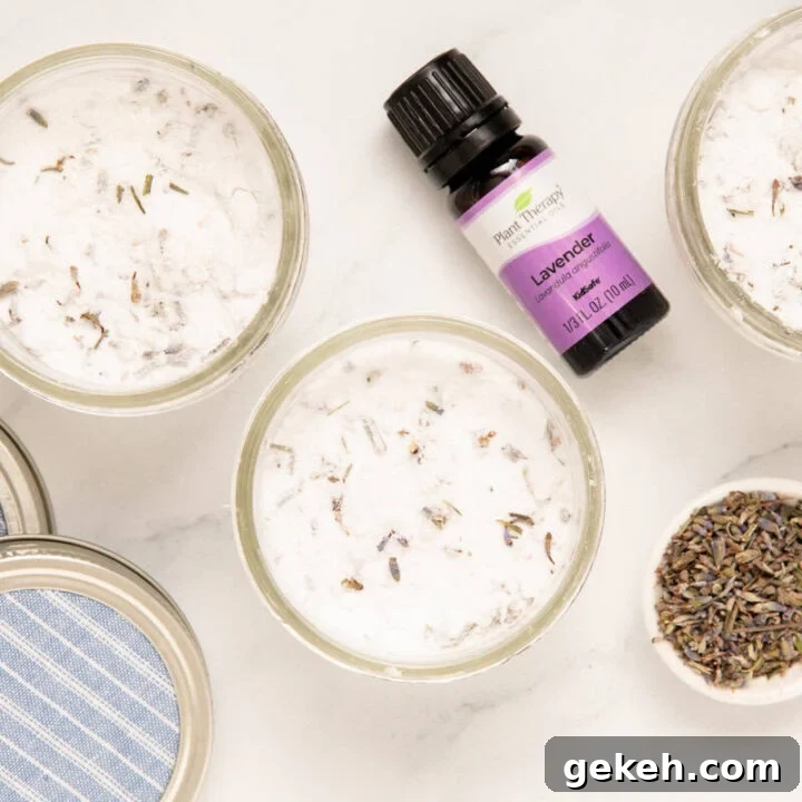mason jars of homemade air freshener with a bottle of lavender essential oil and a spoonful of lavender buds next to it
