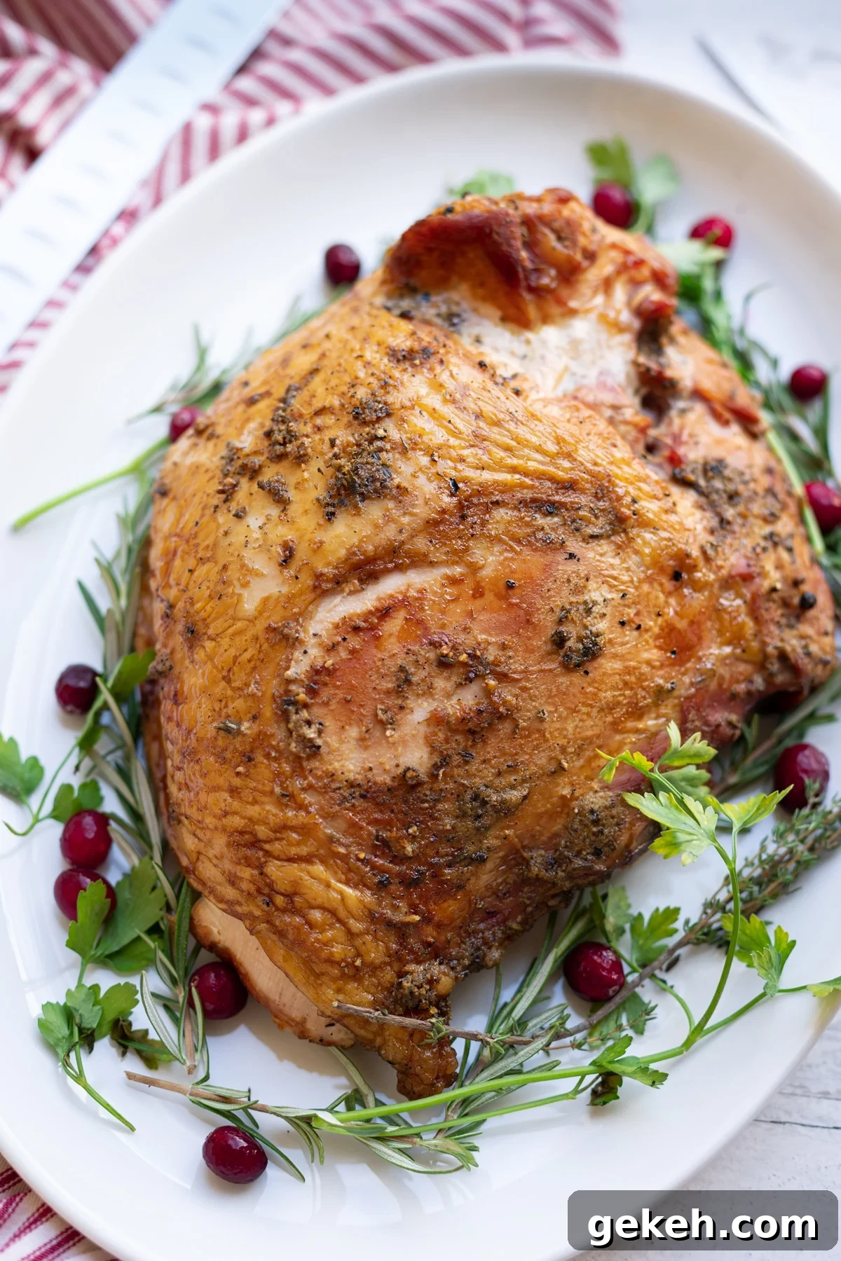 Smoked Turkey Breast on a white platter, cranberries and parsley on plate.