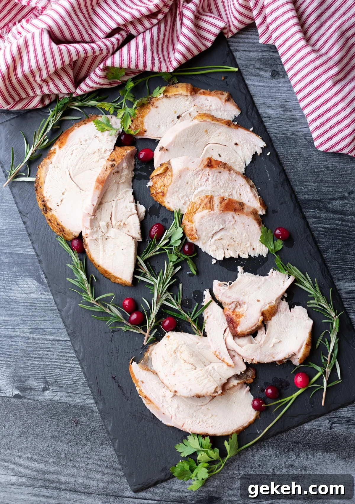Sliced turkey on a platter, rosemary and cranberries on side.