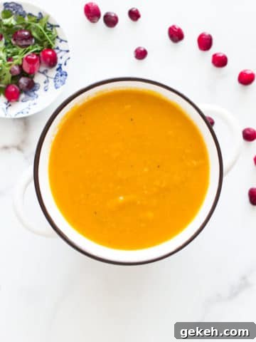 Spoon in a white bowl containing hubbard squash soup.