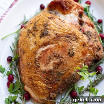 Smoked Turkey Breast on a white platter, cranberries and parsley on plate.