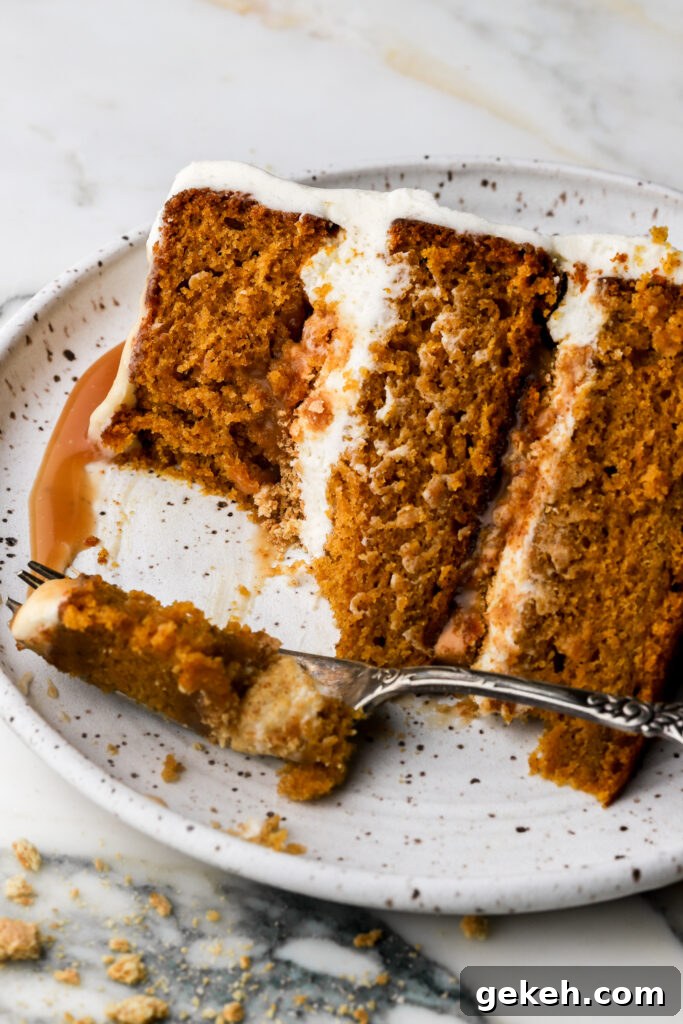 slice of pumpkin cake with cream cheese frosting and caramel sauce on a plate with a bite taken out