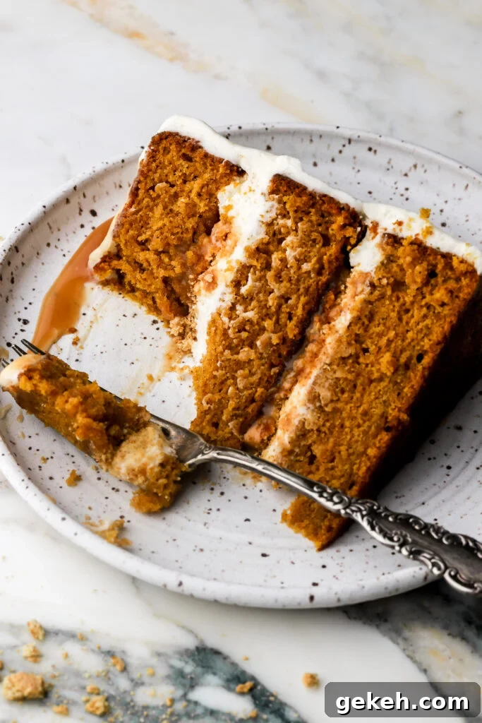 slice of pumpkin cake with cream cheese frosting and caramel sauce on a plate with a bite taken out