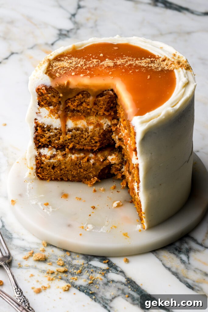 Pumpkin cake frosted with cream cheese frosting and topped with salted caramel sauce, partly cut in to 