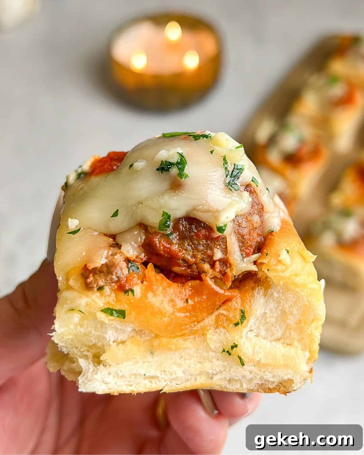 Hawaiian Roll Meatball Sliders with Tangy Pineapple Glaze 9 hand holding a meatball slider over the counter