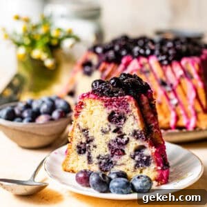 Moist Lemon Blueberry Pound Cake Recipe 14 a slice of lemon blueberry pound cake on a cake plate topped with blueberry lemon glaze and blueberry compote on top.