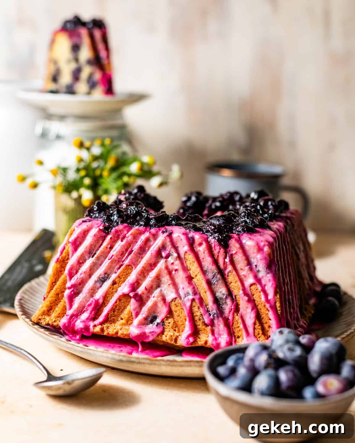 Moist Lemon Blueberry Pound Cake Recipe 9 blueberry lemon pound cake on a plate topped with lemon blueberry glaze and a blueberry compote on top.