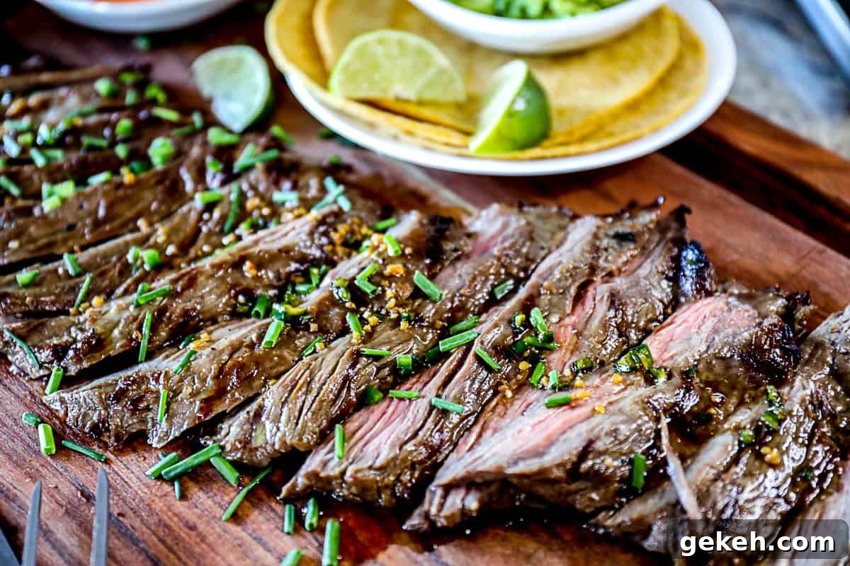 Side shot of platter of skirt steak for tacos with corn taco shells and limes.