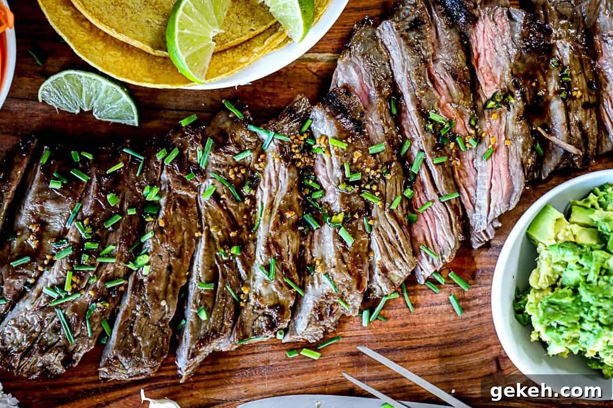 Top down shot of sliced grilled skirt steak with taco ingredients on a serving board.