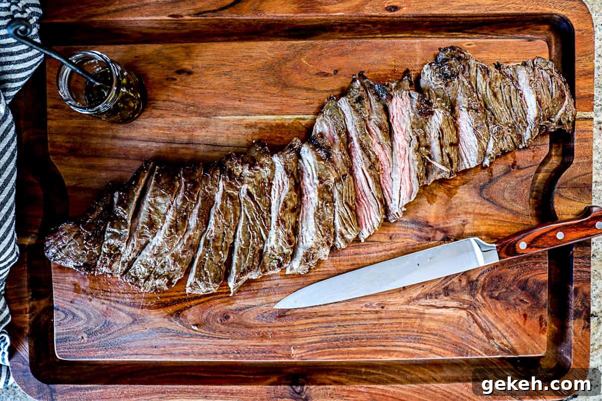 Top down shot of resting steak on a cutting board after grilling with a side of marinade.