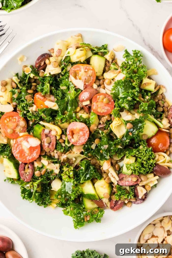 Protein-Packed Lentil and Kale Salad with Lemon Tahini Dressing 7 A lentil kale salad with tomato, almonds, cucumber and artichoke hearts in a bowl.
