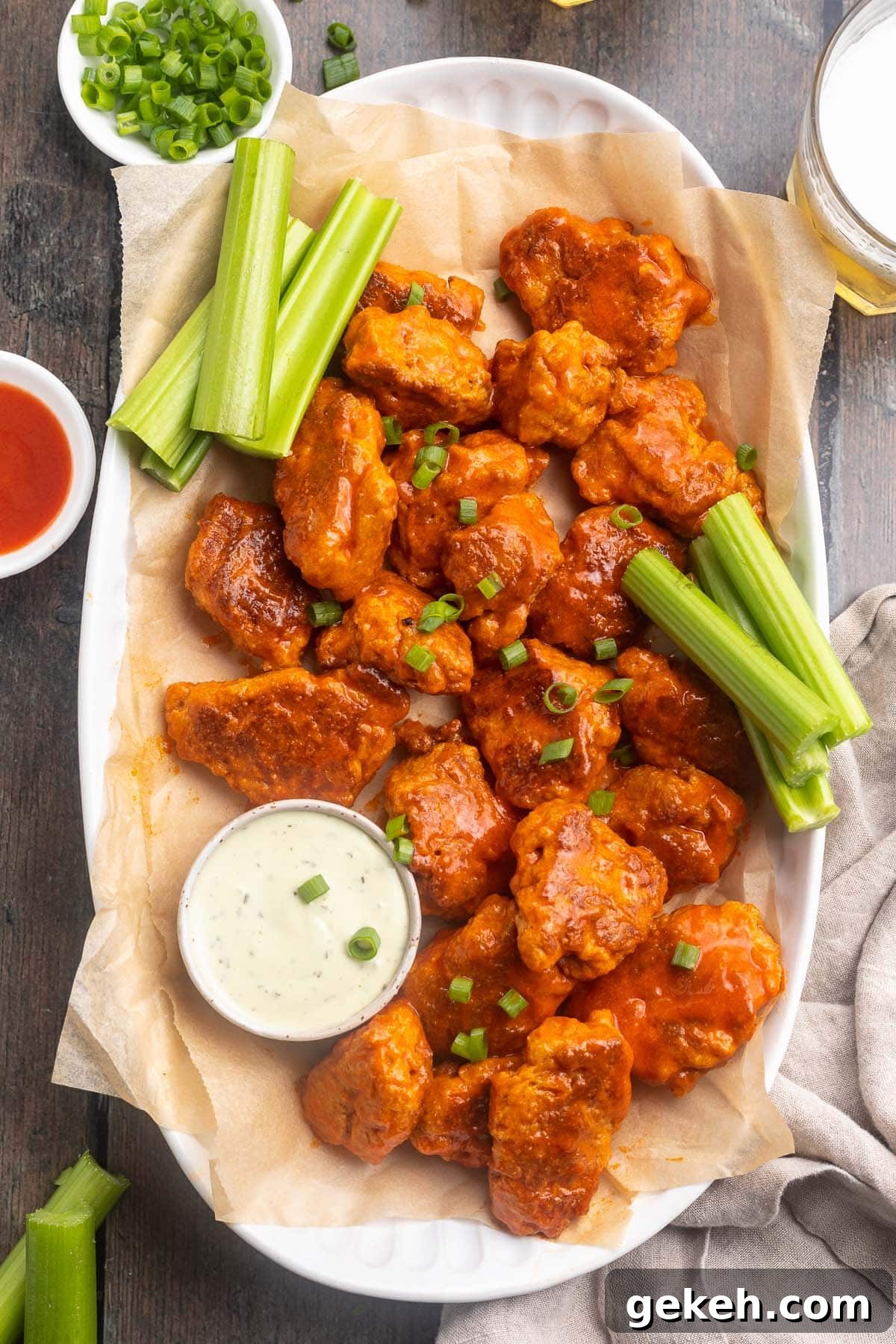 Buffalo-Style Seitan Wings with Spicy Vegan Sauce 3 Buffalo sauced seitan wings on a platter with ranch dressing and celery.