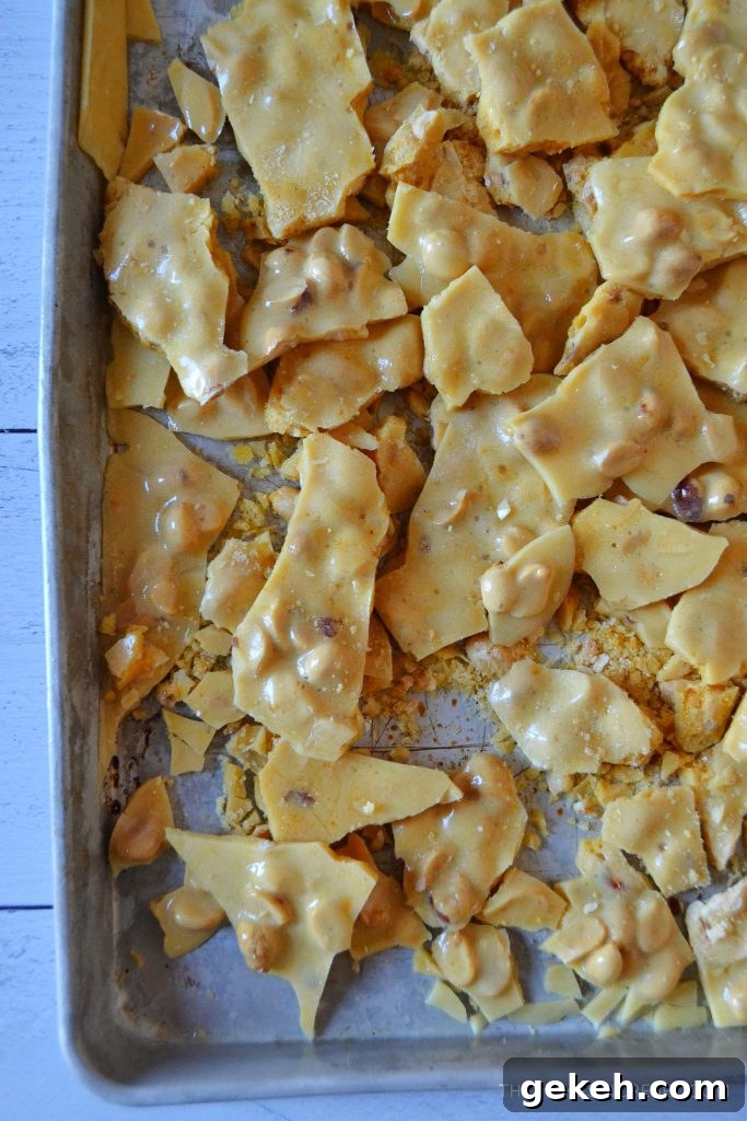 a silver jelly roll pan with peanut brittle pieces all over it
