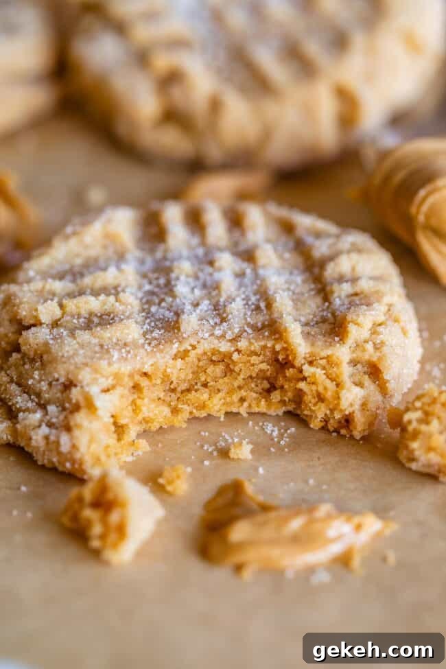 Chewy Peanut Butter Cookie Recipe That Melts in Your Mouth 3 soft peanut butter cookies, one with a bite taken out and a smear of peanut butter on tray.