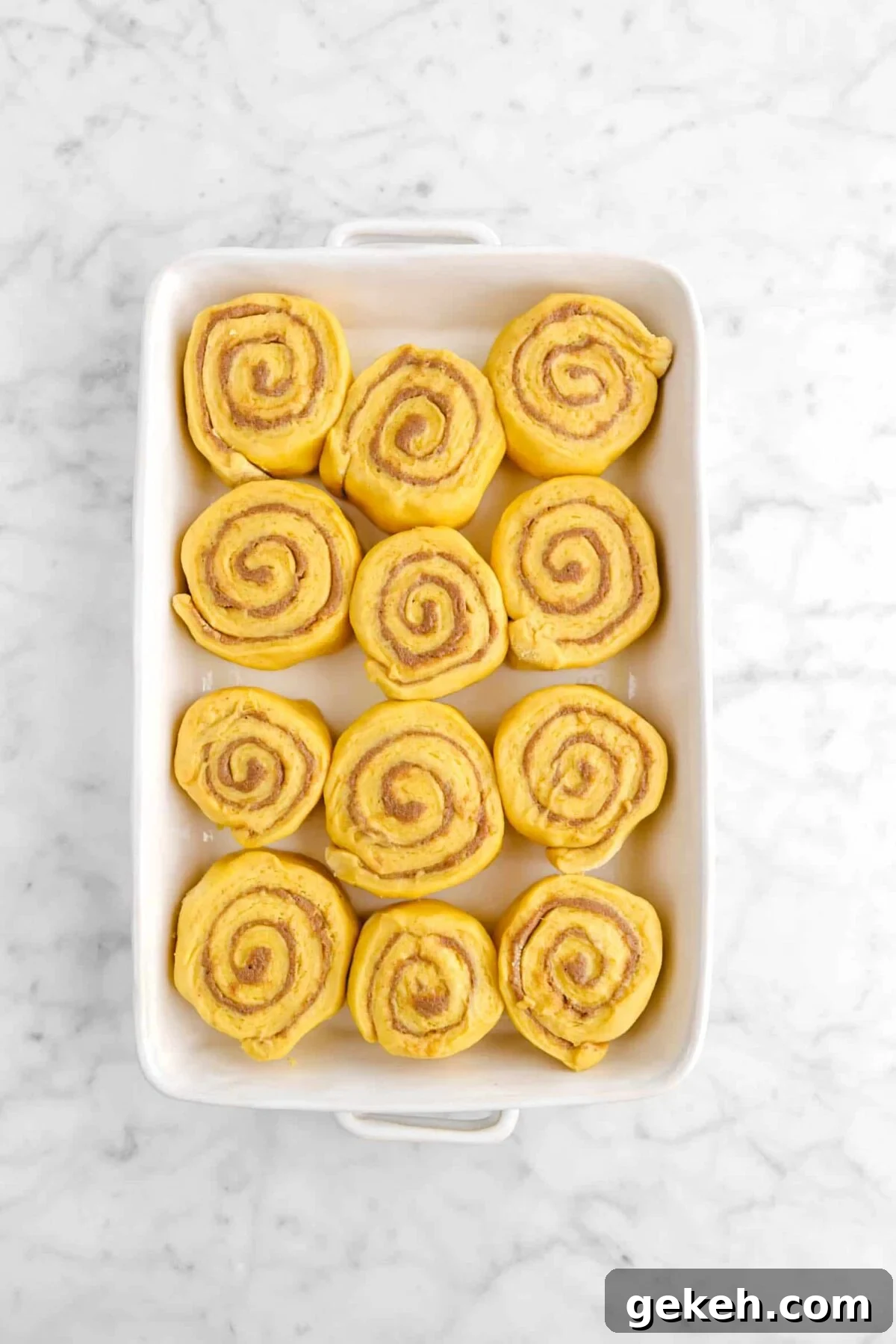 twelve pumpkin cinnamon rolls in white casserole pan