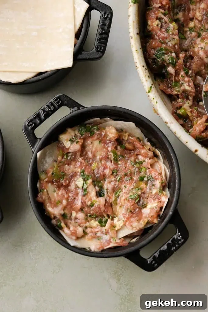 A top-down view shows a mini cocotte layered with pork filling over wonton wrappers, ready for the next layer, with the mixing bowl partially visible beside it.