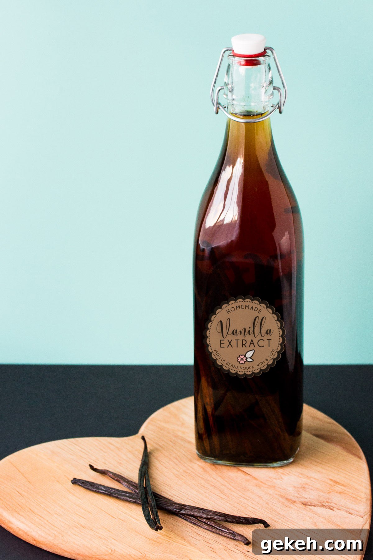 Homemade Vanilla Extract Infused with Rum: Step-by-Step Guide 2 A bottle of vanilla extract on a heart shaped wooden board, text overlay reads: "homemade vanilla extract".