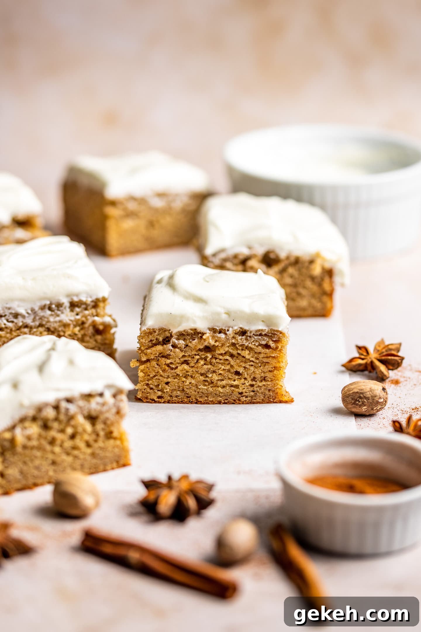 Spiced Banana Snack Cake Recipe for Moist, Flavorful Bites 3 Cake slices surrounded by spices and a bowl of cream cheese frosting