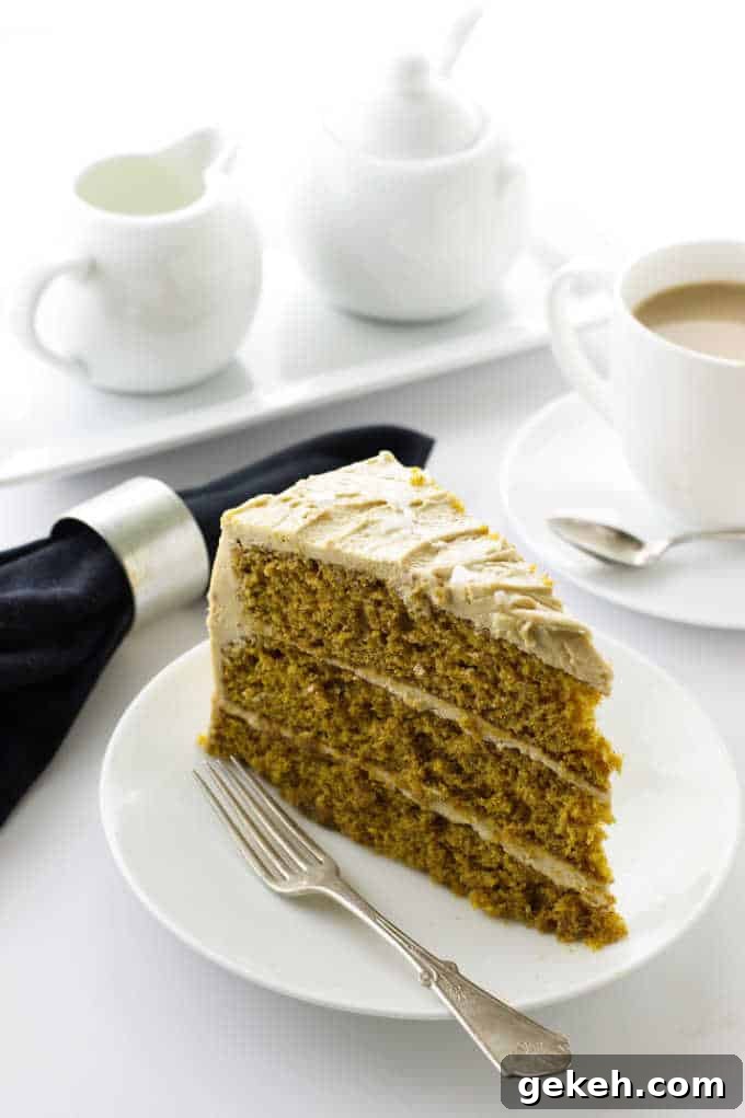 Pumpkin Spice Cake with Salted Caramel Frosting on a plate with fork, cup of coffee, napkin, cream and sugar