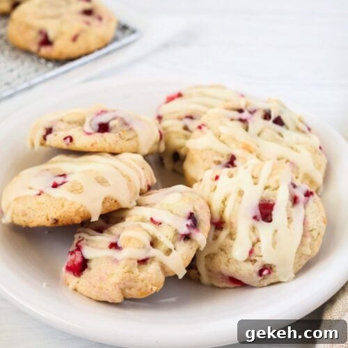 Cake mix cranberry orange cookies served on a white plate. The cookies are topped with a drizzle of icing.