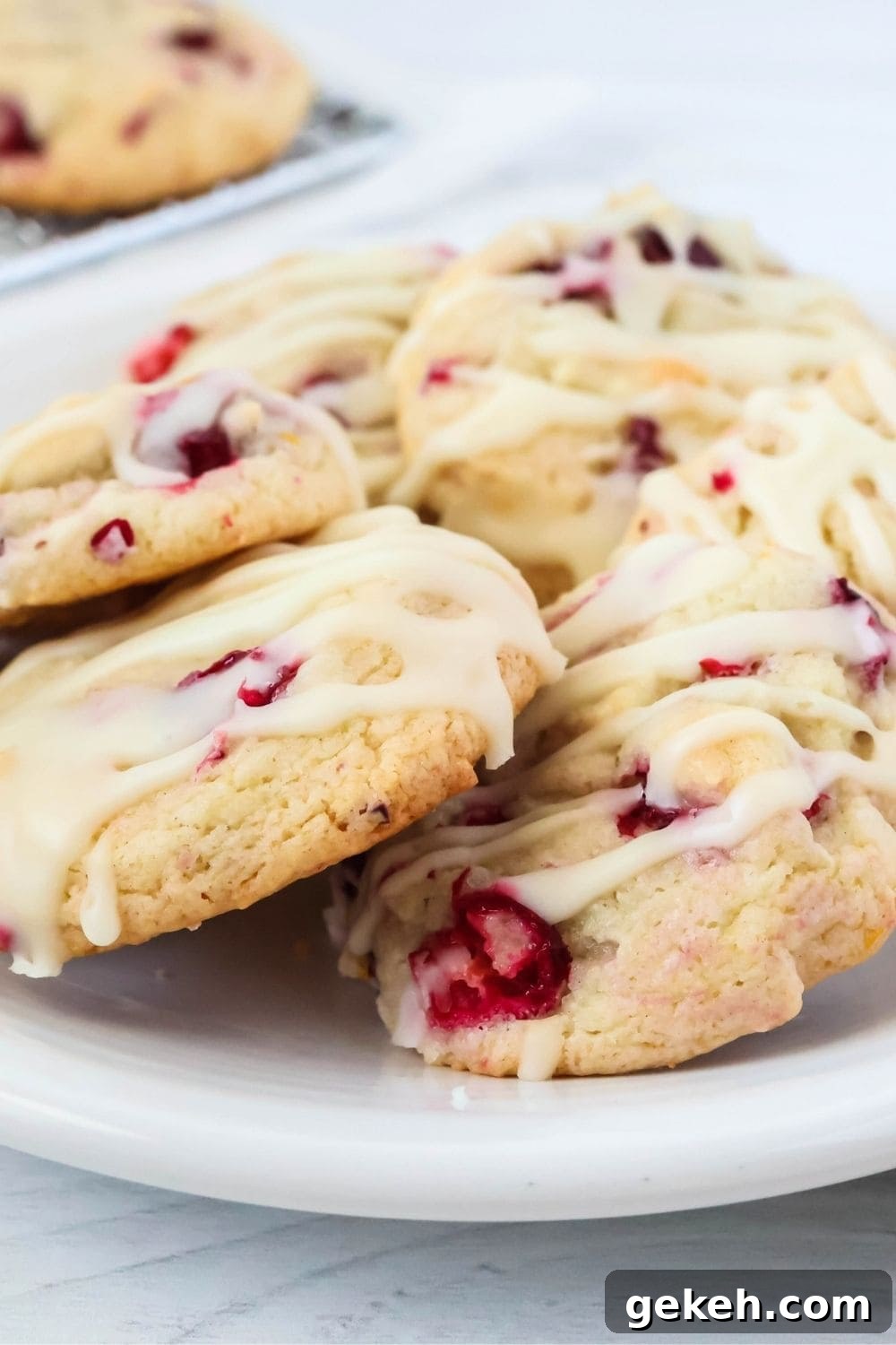 close-up view of a few iced cranberry orange cookies made with cake mix, served on a white plate.