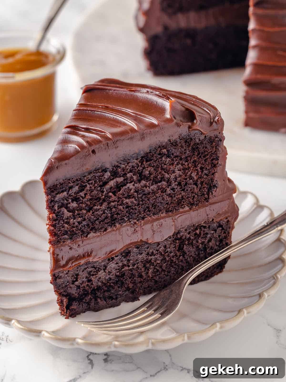 Decadent Guinness Chocolate Cake Recipe with Rich Stout Frosting 22 two layer guinness chocolate cake with caramel fudge frosting on scalloped plate with fork.