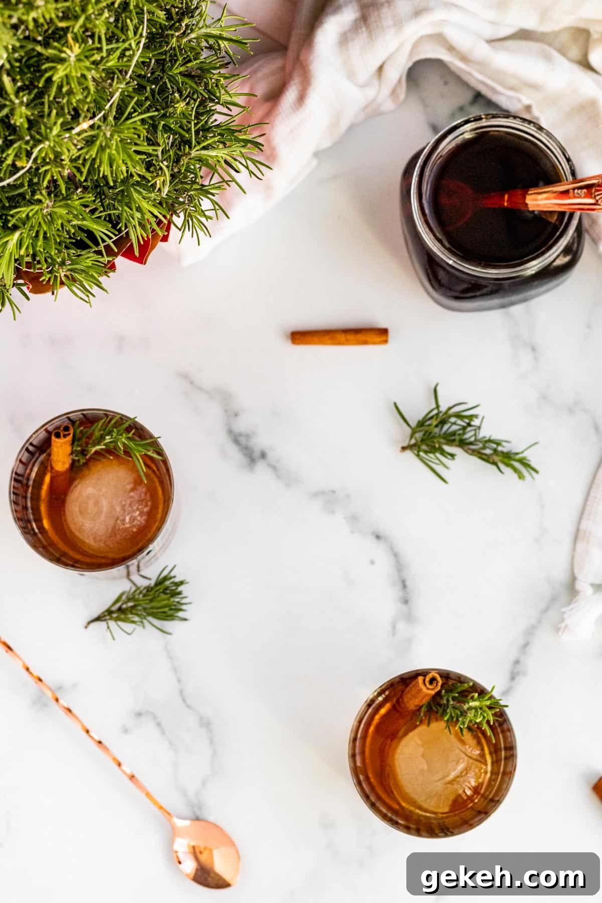 Winter Old-Fashioned Cocktail Recipe: Cozy Seasonal Bourbon Drink 3 overhead view of 2 bourbon cocktails with sprigs of rosemary and cinnamon sticks for garnish