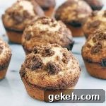 Twelve streusel-topped muffins on a gray and white marble surface.