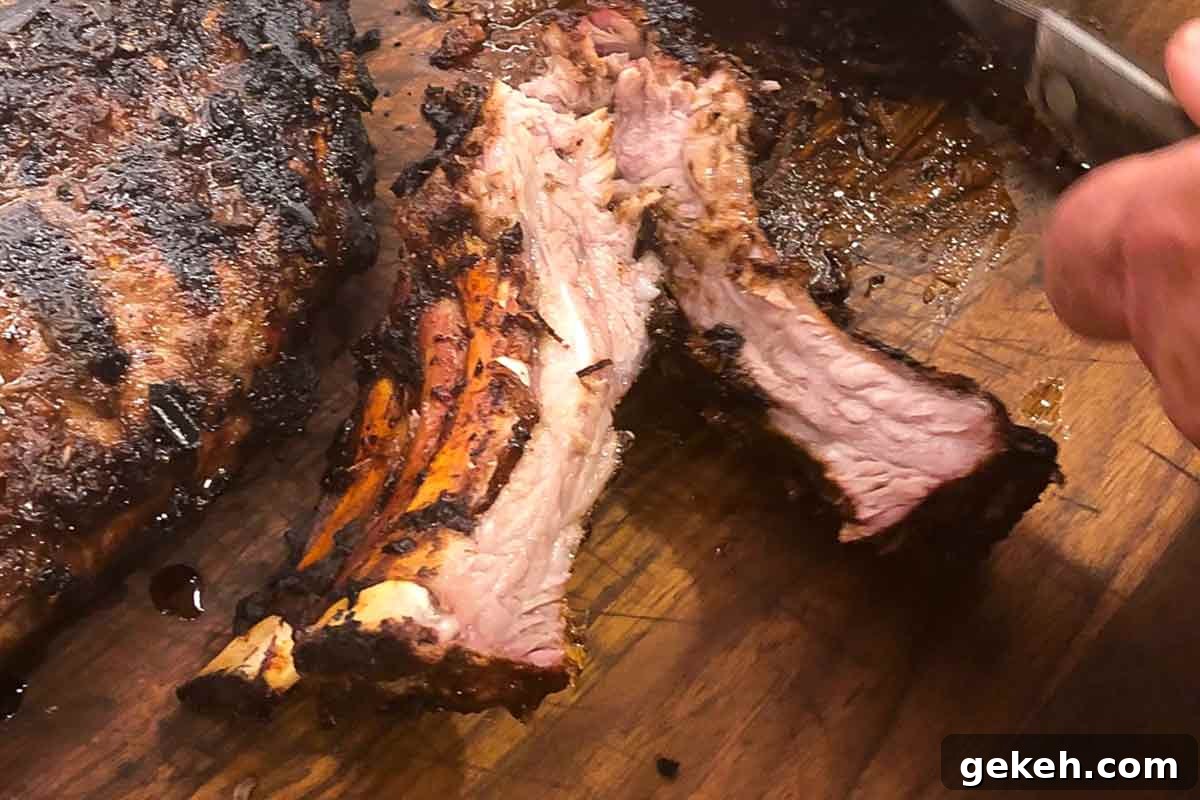 Vietnamese-Style Caramelized Pork Ribs with Garlic and Fish Sauce 6 A person cutting a rack of Vietnamese pork ribs on a wooden cutting board.