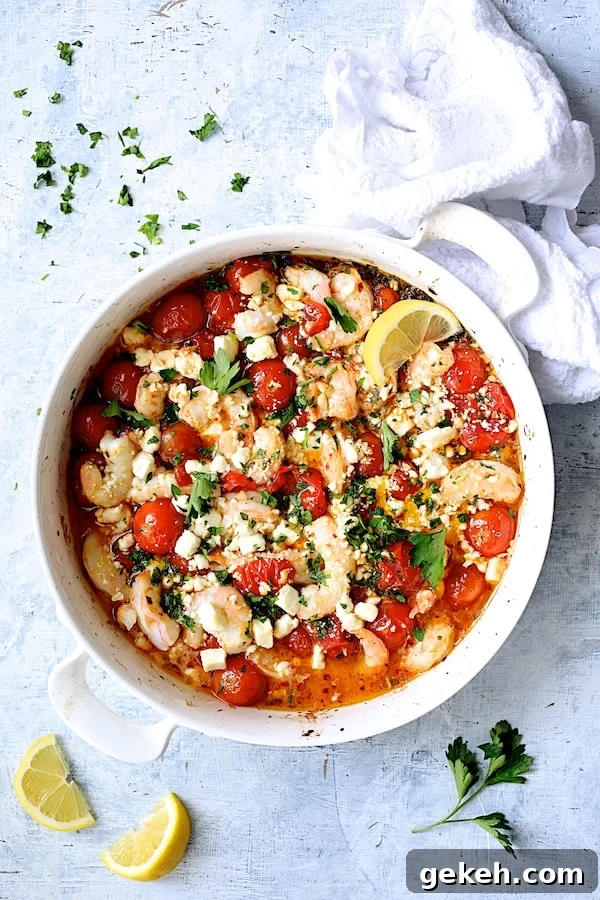 Photo of Spicy Baked Shrimp with Tomatoes and Feta Cheese on pale blue background with white towel, lemon wedges and parsley.