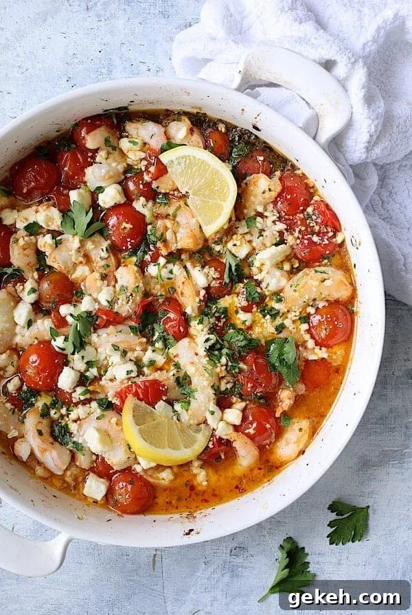 Spicy Baked Shrimp with Tomatoes and Feta Cheese in round white baking dish garnished with parsley and lemon.