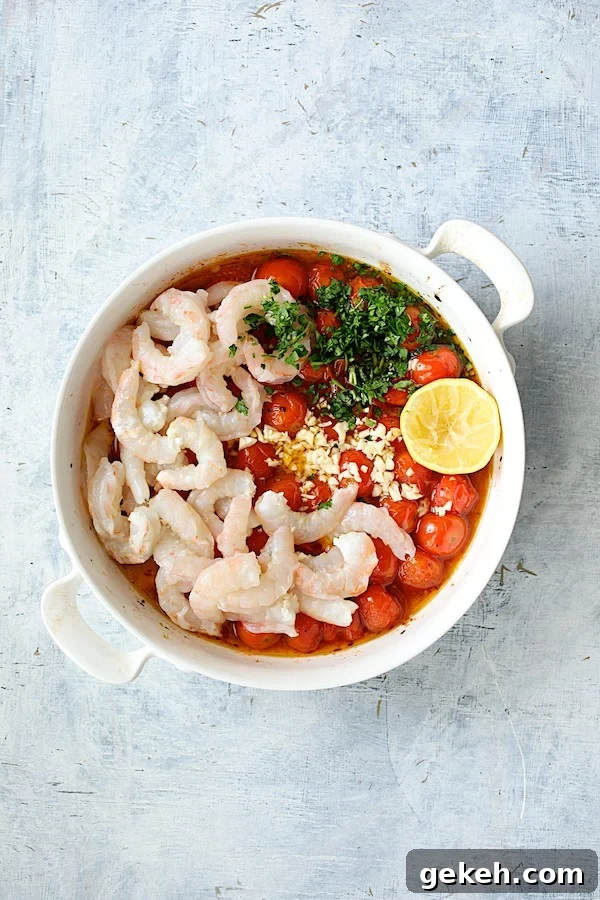 Photo of shrimp, parsley, garlic and lemon added to roasted tomatoes in white baking dish.