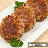 Golden-brown turkey meatloaf patties arranged on a white rectangular platter, garnished with fresh parsley.