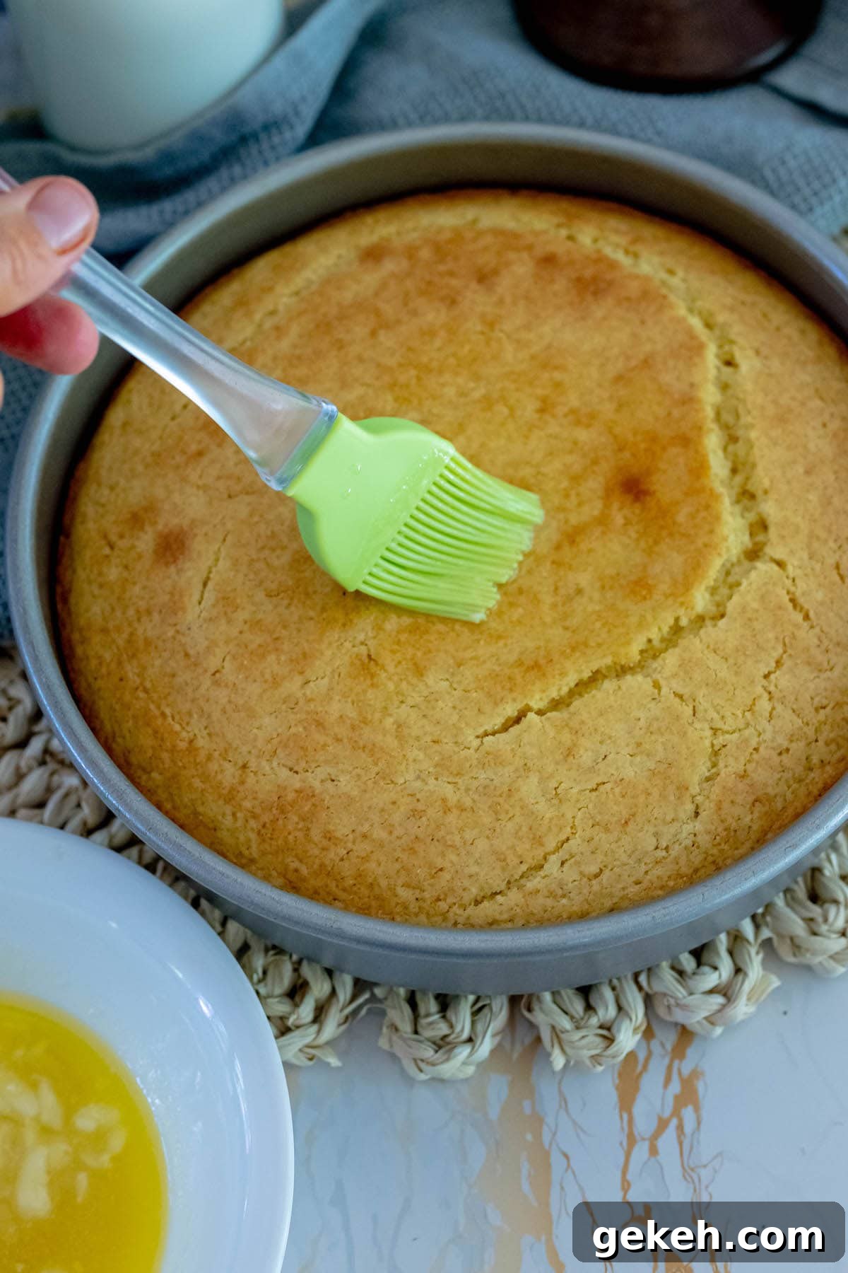 Sour Cream Cornbread Recipe: Moist Southern-Style Loaf 6 baked cornbread in a pan with honey butter being brushed on top