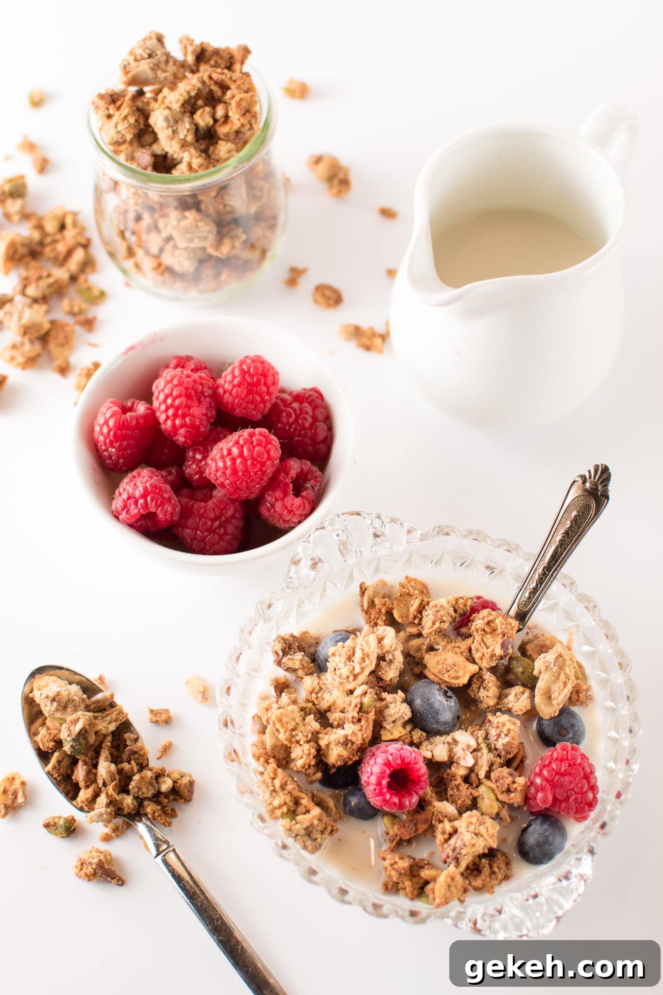 Maple Spice Low-Carb Granola — Crispy, Chewy, Gluten-Free Keto 4 A bright white breakfast table with a bowls of low carb granola, fresh raspberries and almond milk.