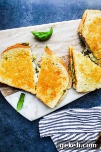 Vegetarian grilled goat cheese sandwich with pesto and arugula. Overhead shot of two grilled cheese sandwiches on a cutting board sliced in half.