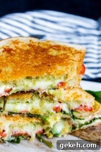 Stacked grilled goat cheese sandwiches on a cutting board. Angle shot of grilled cheese stacked on top of each other on top of a wood and white marble cutting board.