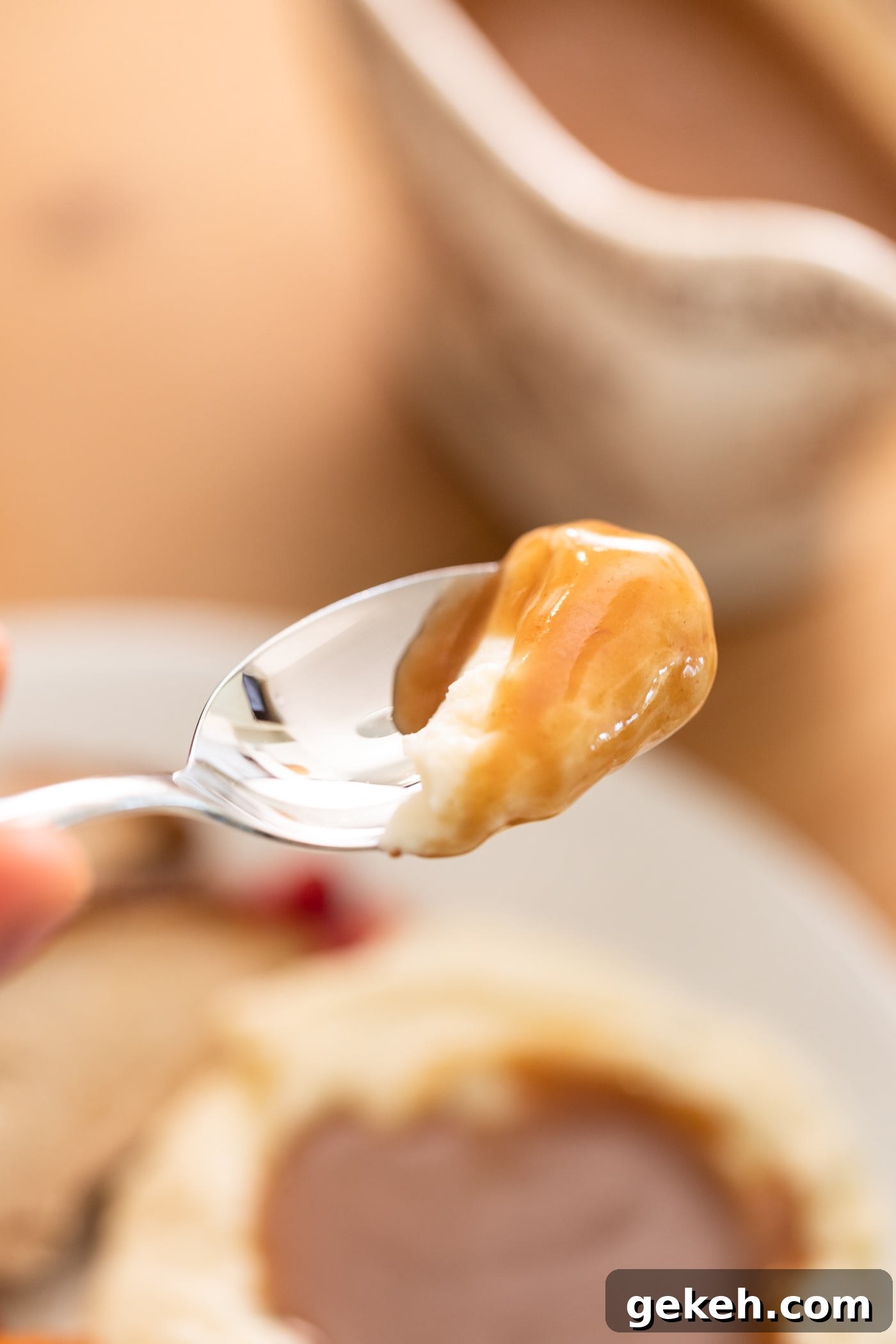 Homemade Gravy Recipe: Smooth, Rich Sauce in Minutes 4 Spoon holding mashed potatoes covered in brown colored gravy with plate in background