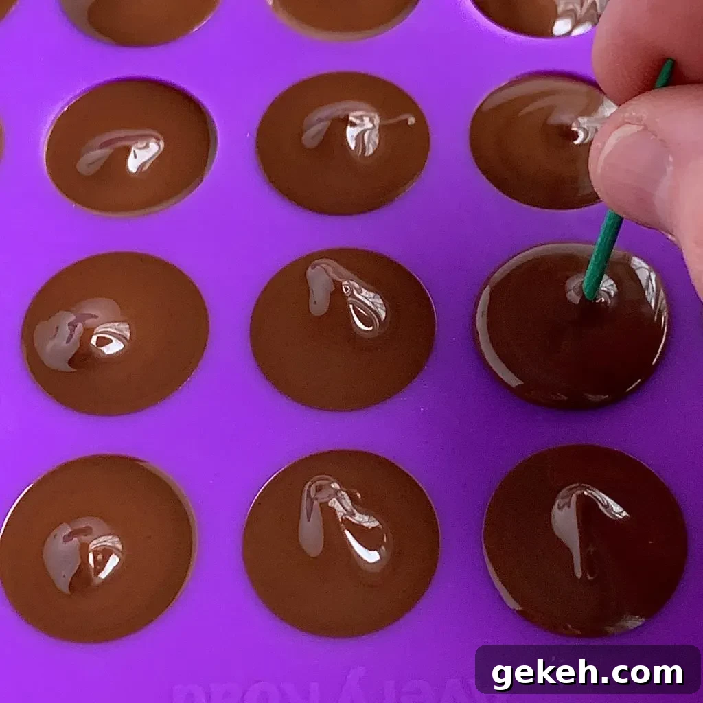Homemade Chocolate Kisses: Simple Recipe for Melt-in-Your-Mouth Treats 5 a toothpick pushing melted chocolate into the tip of a chocolate kiss cavity mold.