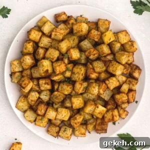 Crispy Air Fryer Breakfast Potatoes Recipe 8 golden cubes of potatoes cut and cooked served on a white plate and garnished with parsley.