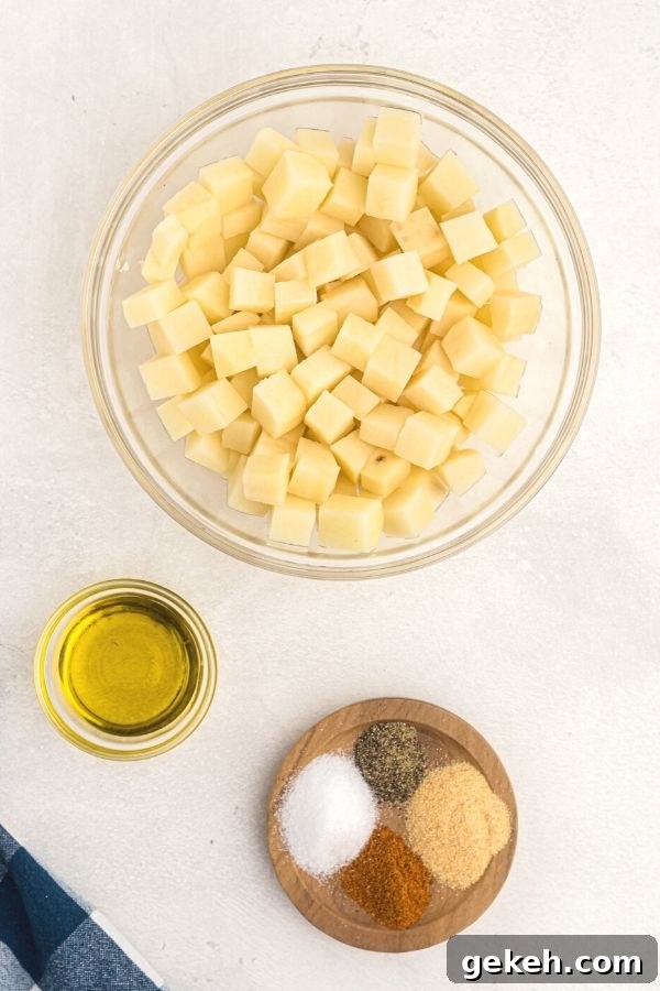 Crispy Air Fryer Breakfast Potatoes Recipe 3 Ingredients needed for breakfast potatoes. Olive oil, seasonings, and cubed potatoes, uncooked.